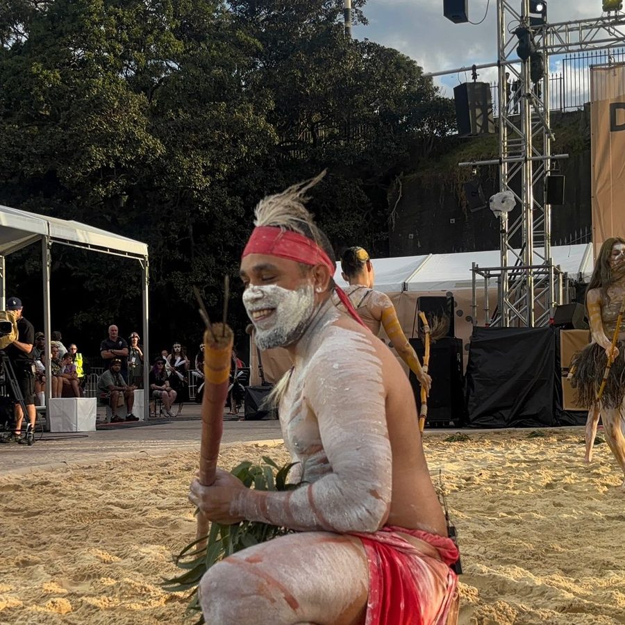 Ryka Ali crouched in the sand mid-performance